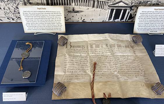 Exhibit case with reproduction papal bull and authentic papals seals, along with interpretive text.