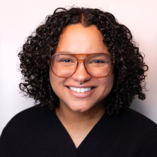 Mallory Wareham smiling and wearing a black sweater and glasses.