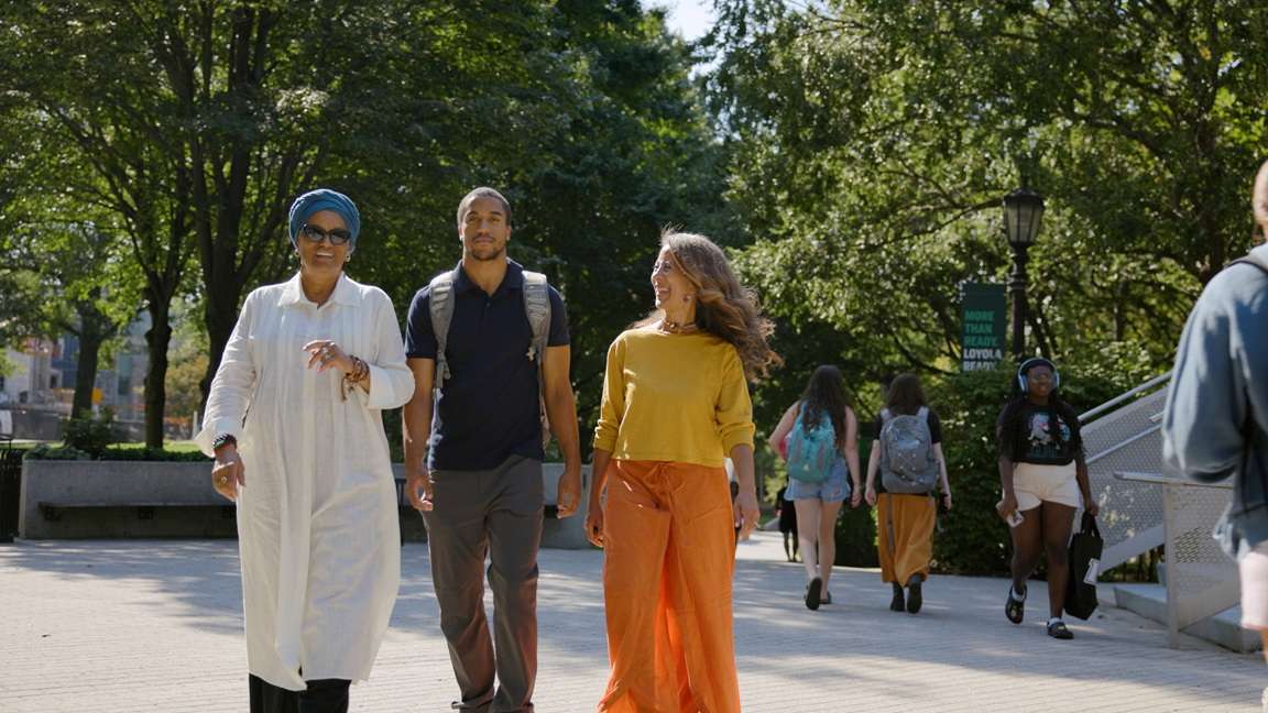 Three individuals walking across the Loyola campus