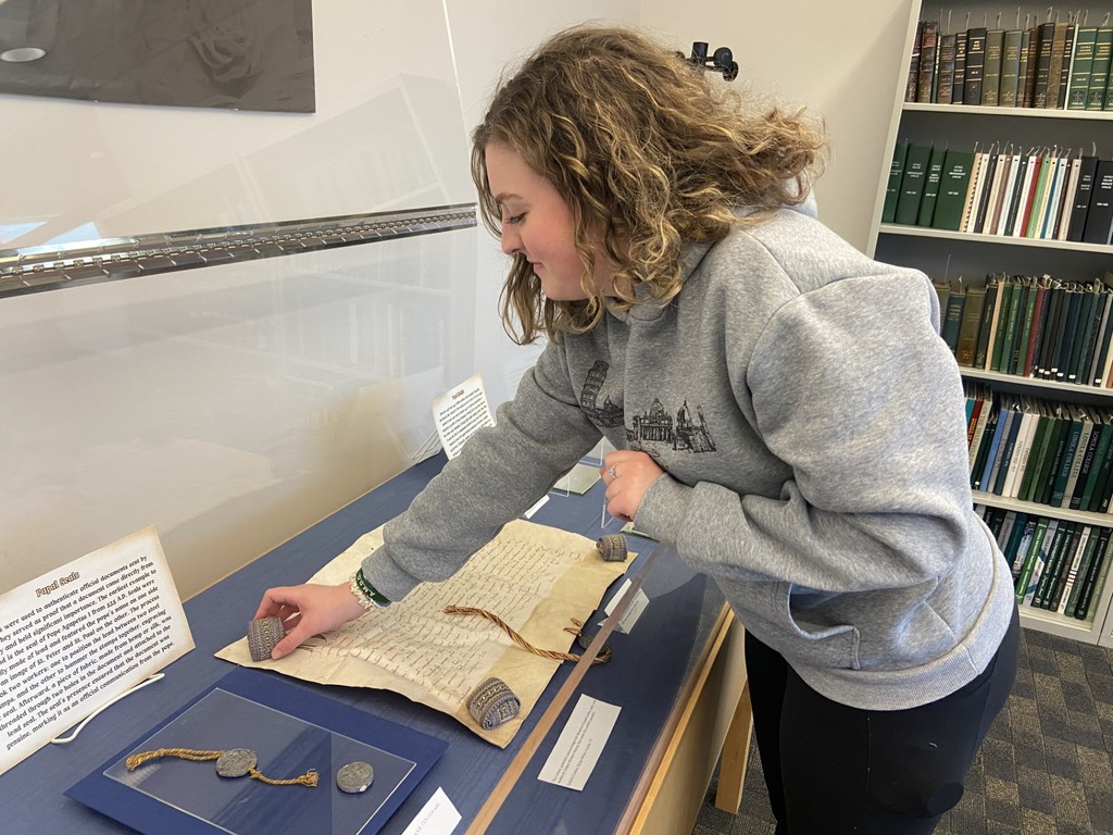 Student curator Rylee Miller (Loyola '25) arranges papal coins exhibit.