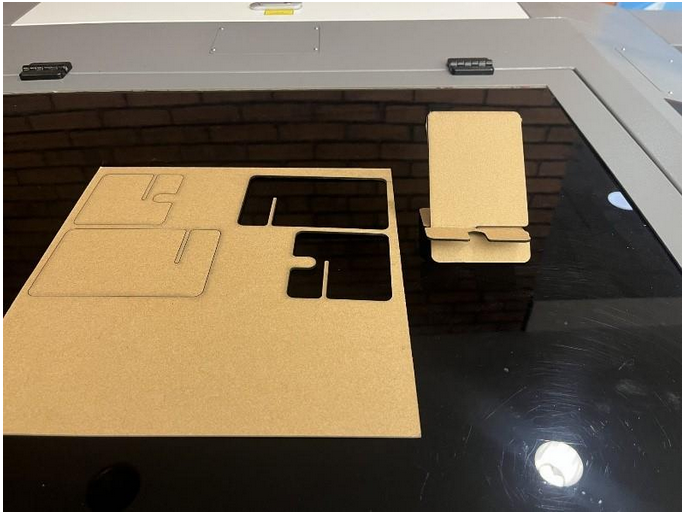 Components of laser cut phone stand for test run.
